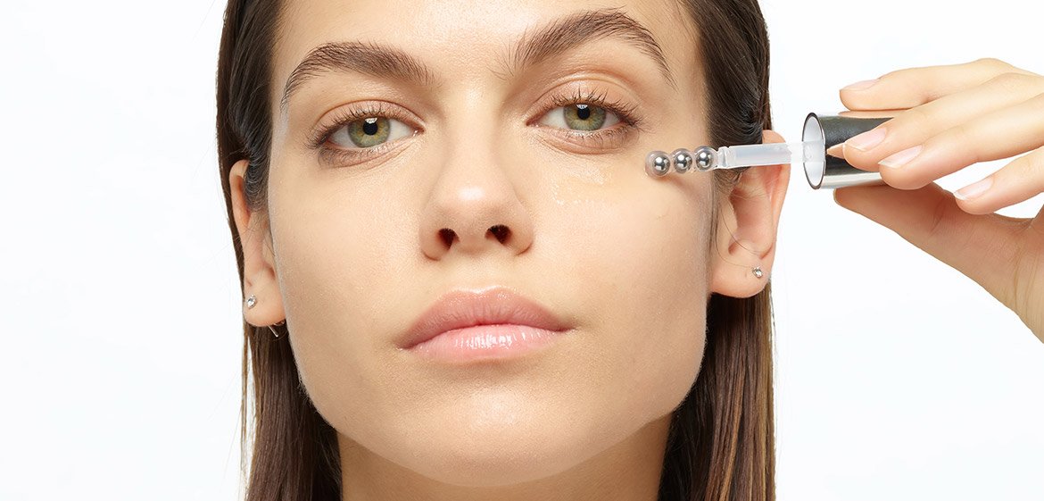 Eine Frau trägt ein Serum mit einer Pipette auf